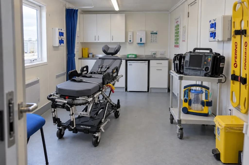 Interior of a LightMed on-site medical clinic cabin with a stretcher, monitoring equipment, Ferno boards and a treatment area.