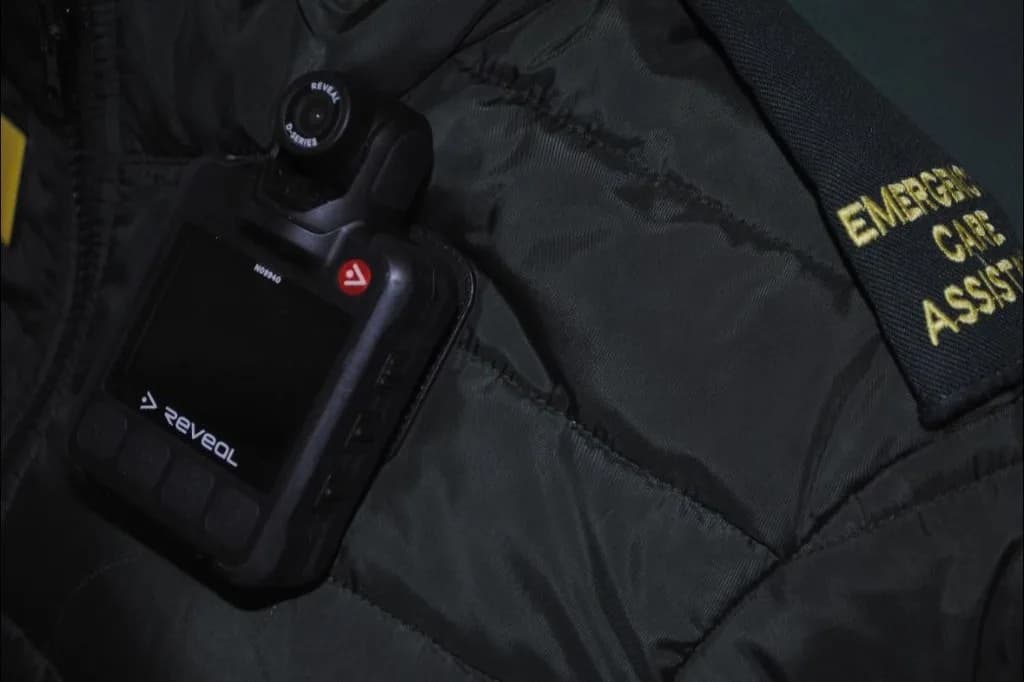 Reveal body-worn camera clipped to a LightMed Emergency Care Assistant jacket.