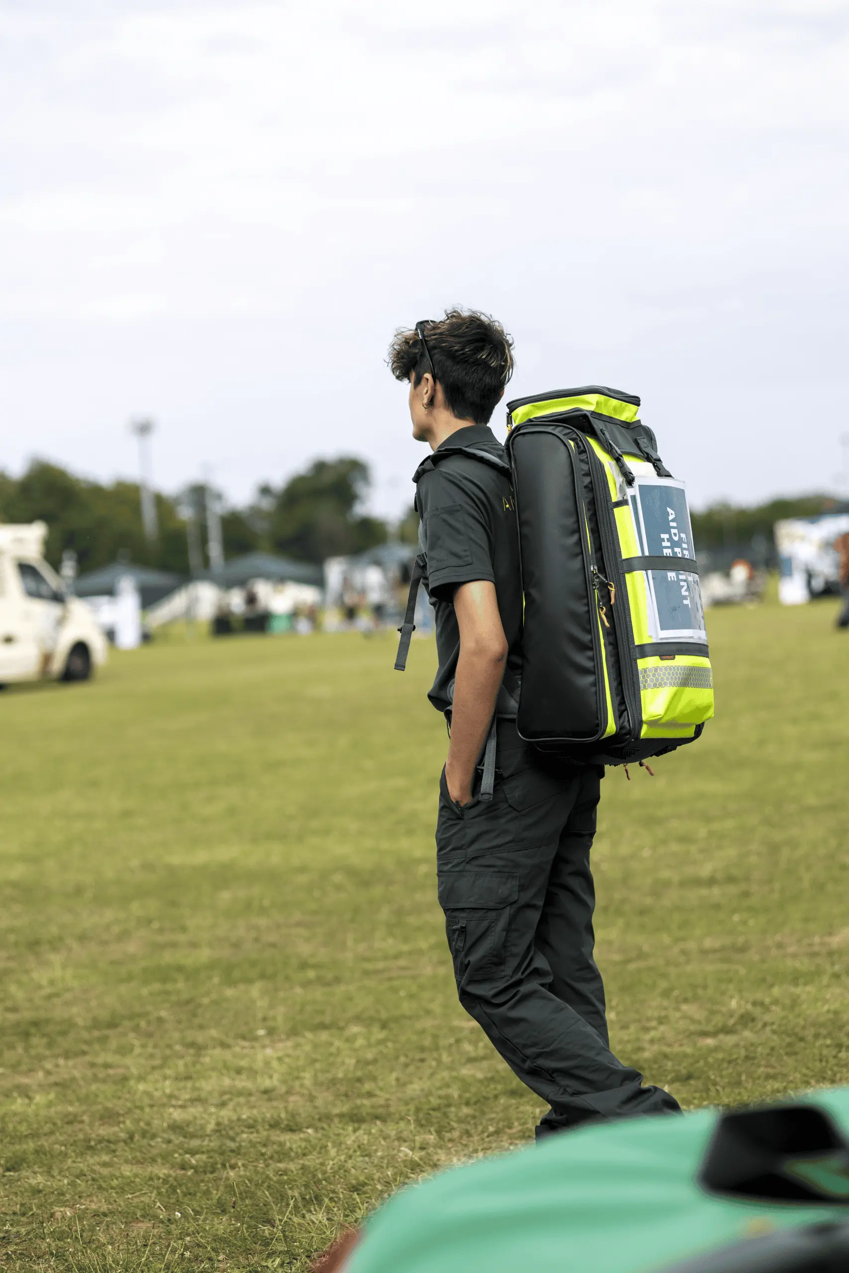 Event medical responder with clinical backpack at an outdoor running event location.